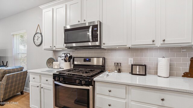 113 Mosaic Dr, Port St Joe, FL 32456 - kitchen featuring stainless steel appliances, white cabinetry, decorative backsplash, and light wood-style flooring