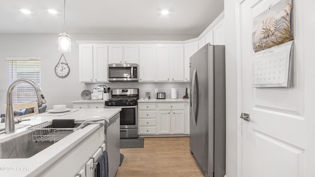 113 Mosaic Dr, Port St Joe, FL 32456 - kitchen featuring appliances with stainless steel finishes, a sink, white cabinetry, decorative backsplash, and decorative light fixtures