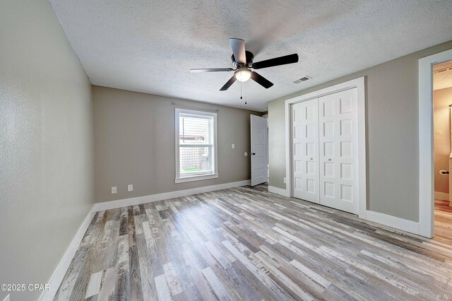 823 Bradley Cir, Lynn Haven, FL 32444 - unfurnished bedroom featuring wood finished floors, baseboards, a closet, a textured ceiling, and ceiling fan