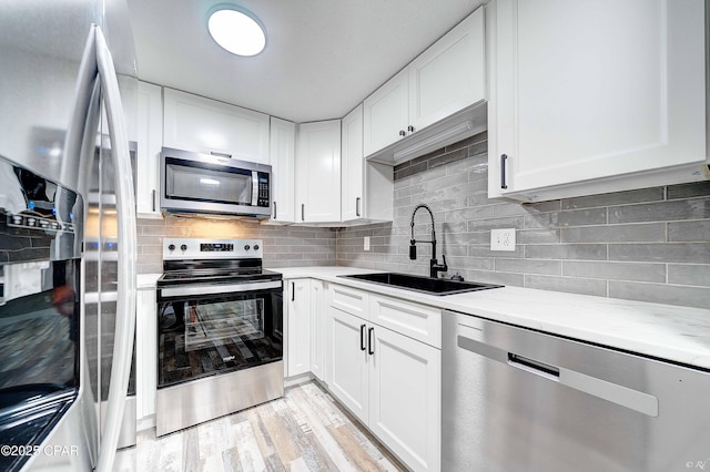 823 Bradley Cir, Lynn Haven, FL 32444 - kitchen with appliances with stainless steel finishes, a sink, tasteful backsplash, white cabinetry, and light wood-style flooring
