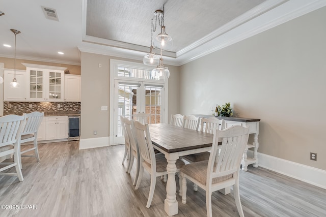 4134 Cobalt Cir Unit Ro14, Panama City Beach, FL 32408 - dining space featuring beverage cooler, a raised ceiling, french doors, light wood-style floors, and ornamental molding