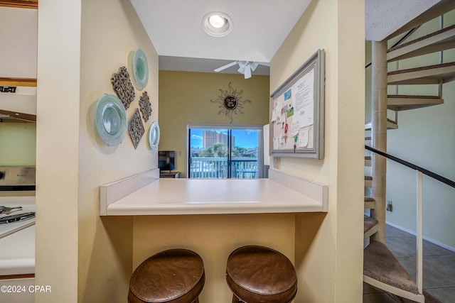 17614 Front Beach Rd Unit 17E, Panama City Beach, FL 32413 - kitchen with white range, exhaust hood, tile patterned floors, a kitchen bar, and baseboards