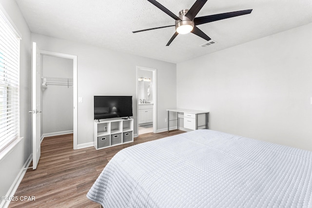 190 White Cap Way, Panama City Beach, FL 32407 - bedroom featuring wood finished floors, a walk in closet, multiple windows, a closet, and a textured ceiling