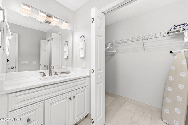 190 White Cap Way, Panama City Beach, FL 32407 - bathroom featuring marble finish floors, vanity, a walk in closet, and baseboards