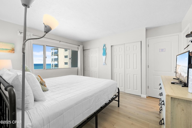 23223 Front Beach Rd Unit C1-502, Panama City Beach, FL 32413 - bedroom featuring multiple closets, light wood-type flooring, and a water view