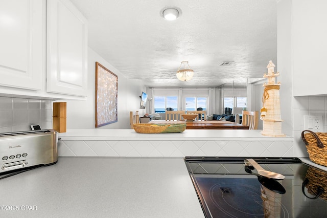 23223 Front Beach Rd Unit C1-502, Panama City Beach, FL 32413 - kitchen featuring white cabinetry, tasteful backsplash, a textured ceiling, and light countertops