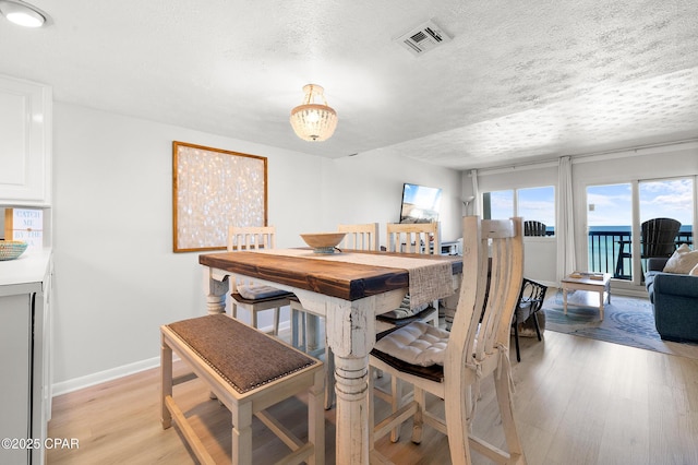 23223 Front Beach Rd Unit C1-502, Panama City Beach, FL 32413 - dining room featuring light wood-style floors, baseboards, and a textured ceiling