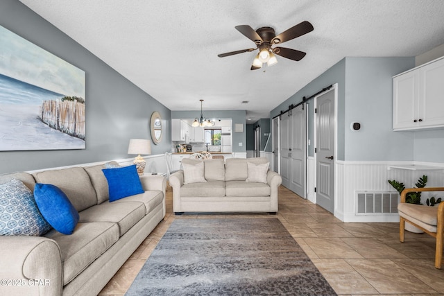 17620 Front Beach Rd Unit P2, Panama City Beach, FL 32413 - living room with ceiling fan, a textured ceiling, a chandelier, and a wainscoted wall
