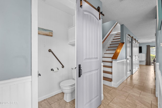 17620 Front Beach Rd Unit P2, Panama City Beach, FL 32413 - bathroom with toilet, wainscoting, tile patterned floors, a decorative wall, and a textured ceiling