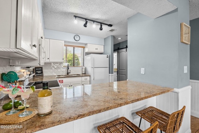 17620 Front Beach Rd Unit P2, Panama City Beach, FL 32413 - kitchen featuring white appliances, a sink, a barn door, track lighting, and a textured ceiling