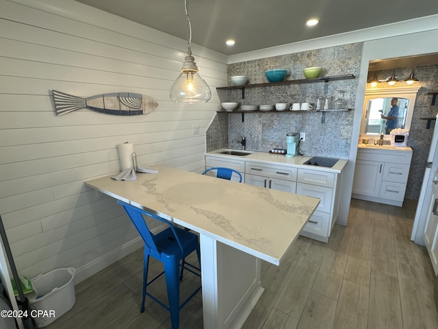 14401 Front Beach Rd Unit 221, Panama City Beach, FL 32413 - kitchen with a sink, decorative backsplash, a kitchen breakfast bar, white cabinetry, and wood finished floors