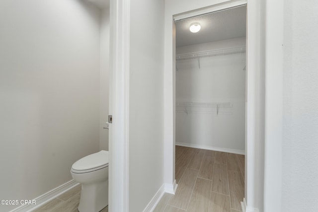 101 Loblolly Ct, Panama City Beach, FL 32413 - bathroom featuring toilet, wood tiled floors, baseboards, and a spacious closet