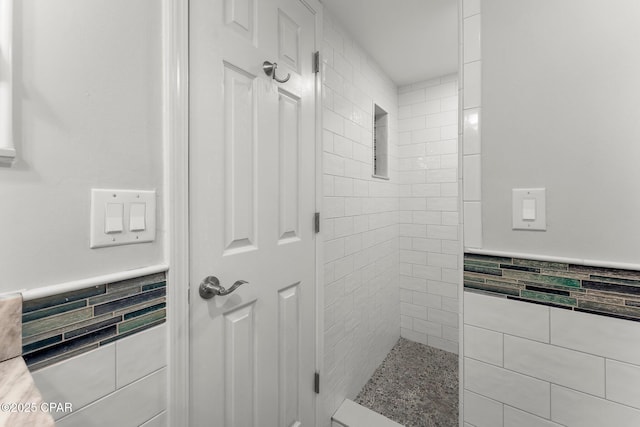 23223 Front Beach Rd Unit 335, Panama City Beach, FL 32413 - bathroom featuring tile walls, a wainscoted wall, and tiled shower