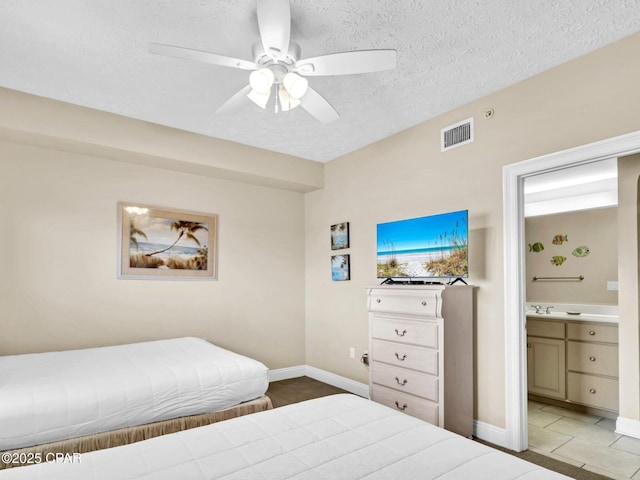 7115 Thomas Dr Unit 602, Panama City Beach, FL 32408 - tiled bedroom featuring ensuite bath, a textured ceiling, and a ceiling fan