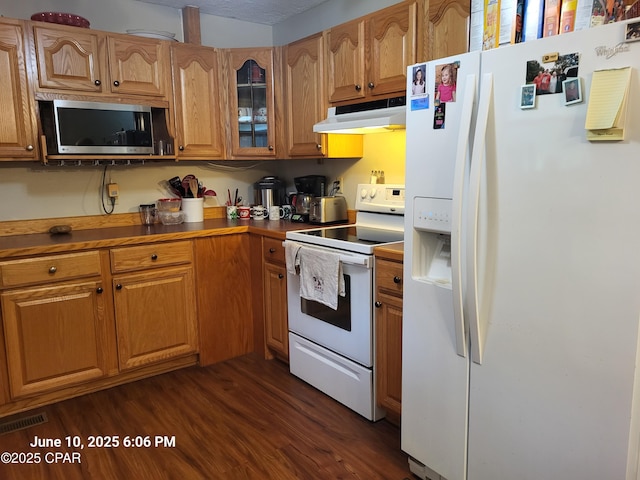 4881 Tall Pine Dr, Marianna, FL 32446 - kitchen with white appliances, under cabinet range hood, dark wood-style flooring, glass insert cabinets, and brown cabinetry