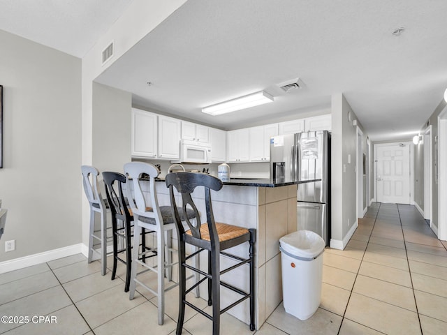 15817 Front Beach Rd Unit 1-204, Panama City Beach, FL 32413 - kitchen featuring white microwave, stainless steel fridge, light tile patterned floors, a peninsula, and a kitchen bar