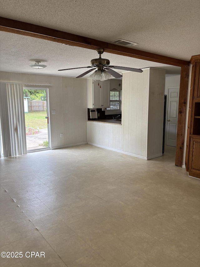 5360 Constitution Rd, Crestview, FL 32539 - unfurnished living room with plenty of natural light, ceiling fan, a textured ceiling, beamed ceiling, and wooden walls