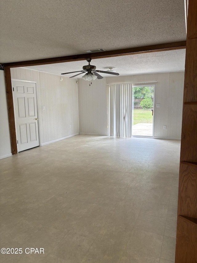 5360 Constitution Rd, Crestview, FL 32539 - unfurnished room featuring wooden walls, a textured ceiling, ceiling fan, beamed ceiling, and light flooring
