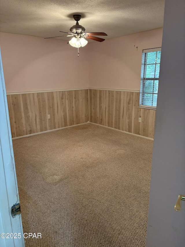 5360 Constitution Rd, Crestview, FL 32539 - empty room with ceiling fan, wainscoting, a textured ceiling, wooden walls, and carpet flooring