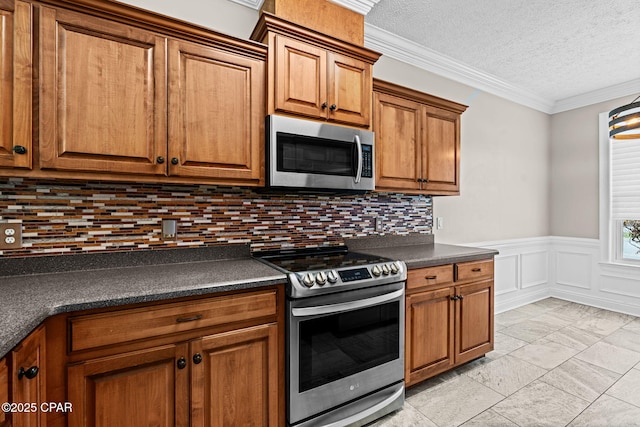 2932 Palmetto Ridge Way, Lynn Haven, FL 32444 - kitchen featuring stainless steel appliances, dark countertops, brown cabinets, tasteful backsplash, and wainscoting