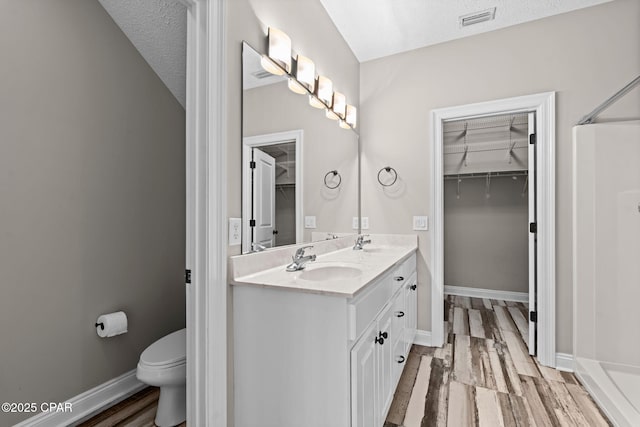 2932 Palmetto Ridge Way, Lynn Haven, FL 32444 - full bathroom with a spacious closet, double vanity, wood finished floors, a shower, and a textured ceiling