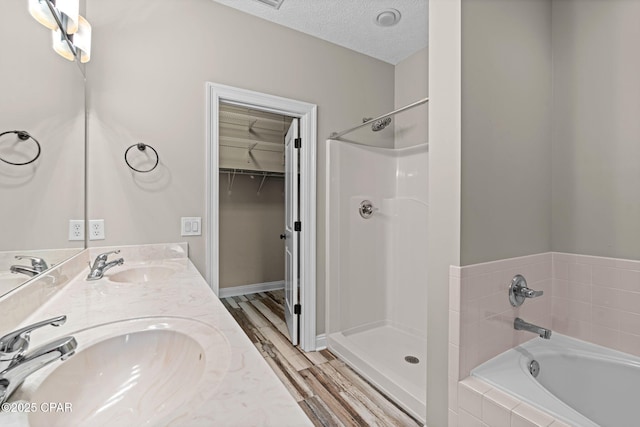 2932 Palmetto Ridge Way, Lynn Haven, FL 32444 - bathroom featuring a garden tub, double vanity, a walk in closet, a walk in shower, and a textured ceiling