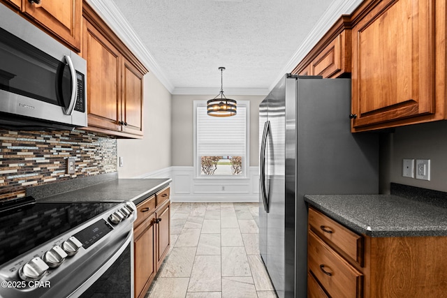 2932 Palmetto Ridge Way, Lynn Haven, FL 32444 - kitchen featuring appliances with stainless steel finishes, dark countertops, brown cabinetry, crown molding, and wainscoting