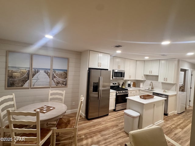 116 Damon Cir Unit C, Panama City Beach, FL 32407 - kitchen with appliances with stainless steel finishes, light wood finished floors, white cabinetry, light countertops, and a center island