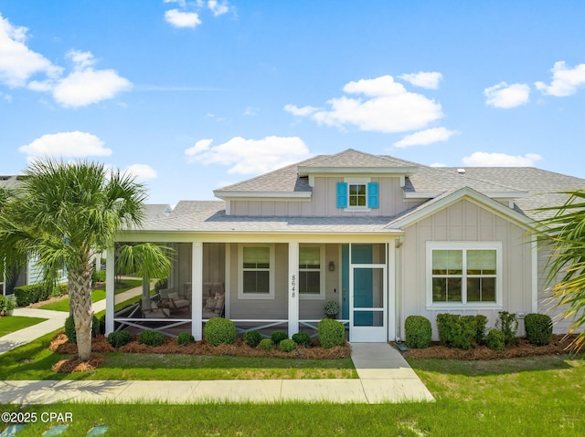 8648 Conch Shell Ct, Panama City Beach, FL 32413 - view of front of house featuring board and batten siding, roof with shingles, a front yard, and a porch