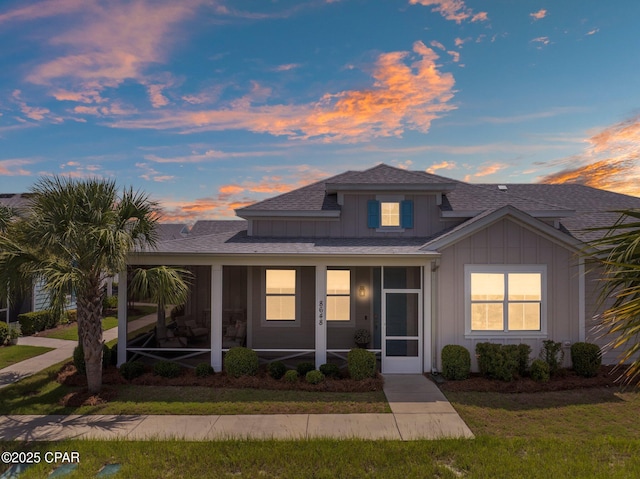 8648 Conch Shell Ct, Panama City Beach, FL 32413 - view of front facade with board and batten siding, roof with shingles, a sunroom, and a front yard