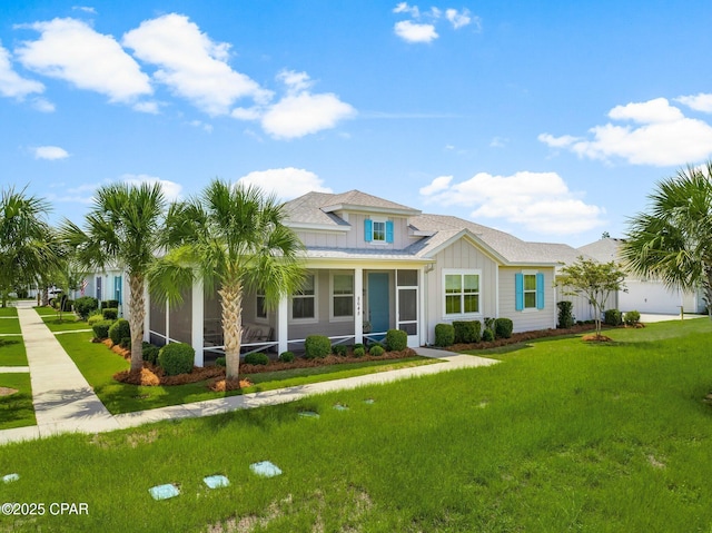 8648 Conch Shell Ct, Panama City Beach, FL 32413 - view of front facade with board and batten siding, a front lawn, roof with shingles, and a sunroom
