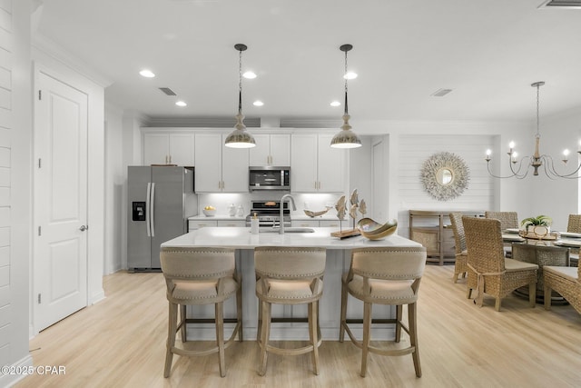 8648 Conch Shell Ct, Panama City Beach, FL 32413 - kitchen featuring appliances with stainless steel finishes, crown molding, a center island with sink, white cabinets, and light wood-style floors