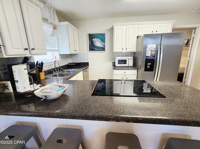 184 White Cap Way, Panama City Beach, FL 32407 - kitchen featuring stainless steel appliances, backsplash, dark countertops, white cabinets, and a kitchen breakfast bar