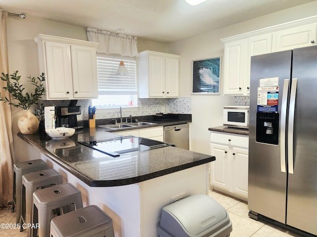 184 White Cap Way, Panama City Beach, FL 32407 - kitchen featuring appliances with stainless steel finishes, a breakfast bar, dark countertops, and a peninsula