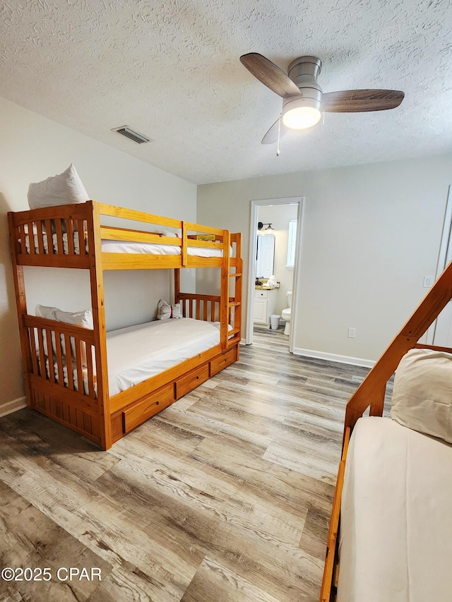 184 White Cap Way, Panama City Beach, FL 32407 - bedroom featuring wood finished floors, a textured ceiling, ensuite bathroom, and ceiling fan