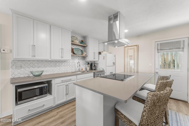 17642 Front Beach Rd Unit B1, Panama City Beach, FL 32413 - kitchen featuring island exhaust hood, stainless steel appliances, open shelves, a breakfast bar area, and light wood-style flooring