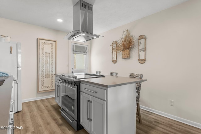 17642 Front Beach Rd Unit B1, Panama City Beach, FL 32413 - kitchen with stainless steel electric range oven, island range hood, light wood-type flooring, freestanding refrigerator, and recessed lighting