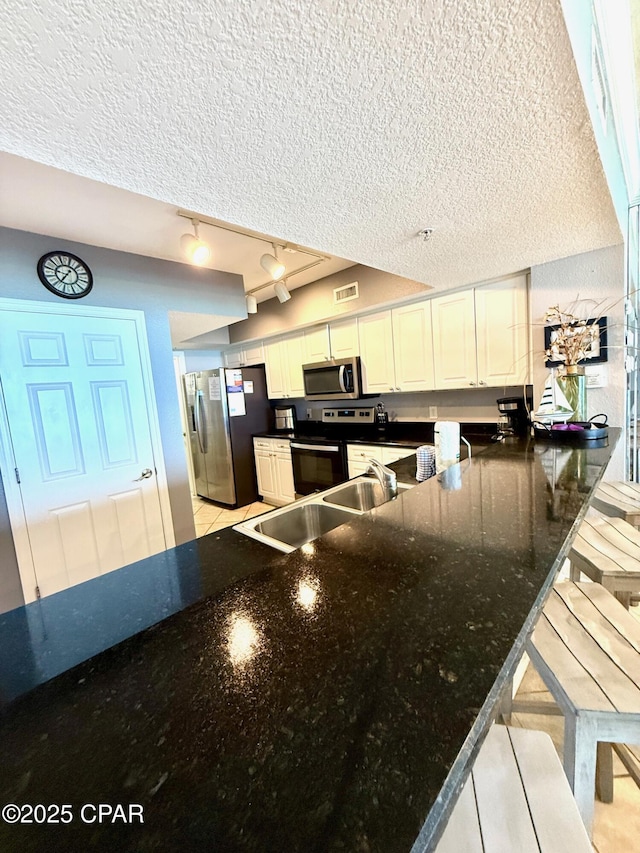 14701 Front Beach Rd Unit 536, Panama City Beach, FL 32413 - kitchen featuring appliances with stainless steel finishes, a textured ceiling, rail lighting, a peninsula, and white cabinetry