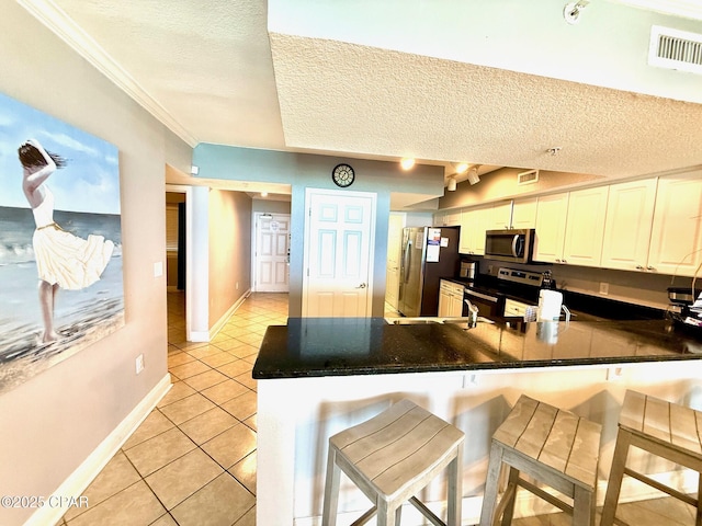 14701 Front Beach Rd Unit 536, Panama City Beach, FL 32413 - kitchen featuring appliances with stainless steel finishes, dark countertops, light tile patterned flooring, a peninsula, and a textured ceiling