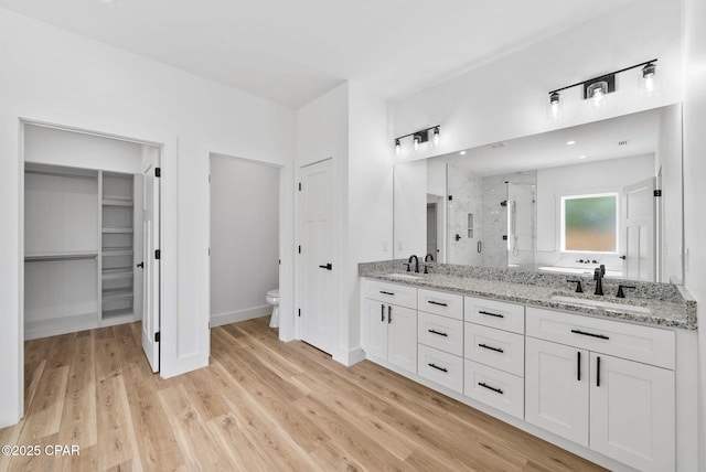 1306 E 26th St, Lynn Haven, FL 32444 - bathroom with a marble finish shower, double vanity, wood finished floors, and a walk in closet