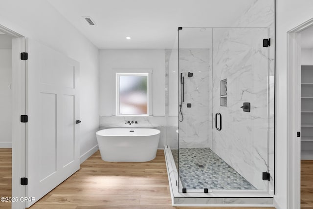 1306 E 26th St, Lynn Haven, FL 32444 - full bath featuring wood finished floors, a soaking tub, a marble finish shower, and recessed lighting