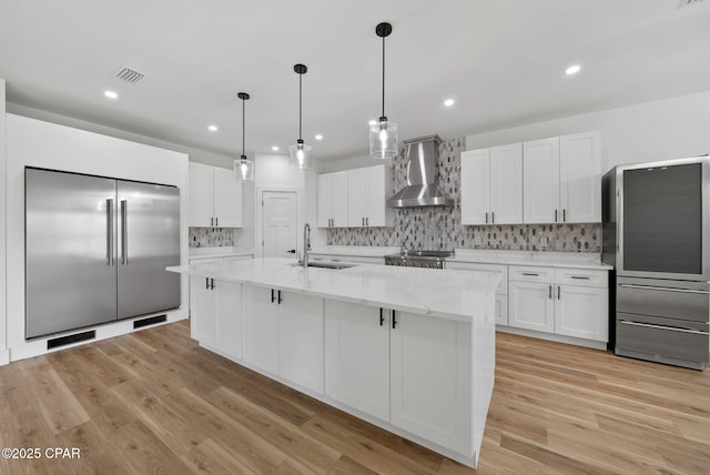 1306 E 26th St, Lynn Haven, FL 32444 - kitchen with wall chimney exhaust hood, freestanding refrigerator, white cabinets, backsplash, and light wood finished floors