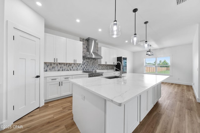 1306 E 26th St, Lynn Haven, FL 32444 - kitchen featuring wall chimney exhaust hood, a center island with sink, white cabinets, backsplash, and recessed lighting