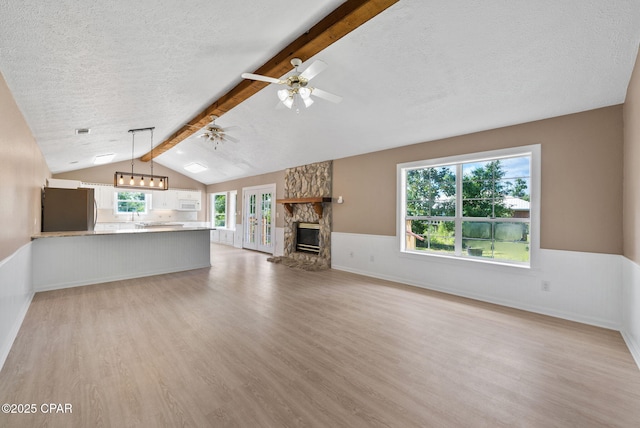 1601 Loblolly Ln, Lynn Haven, FL 32444 - unfurnished living room featuring light wood-style flooring, a textured ceiling, wainscoting, a fireplace, and ceiling fan