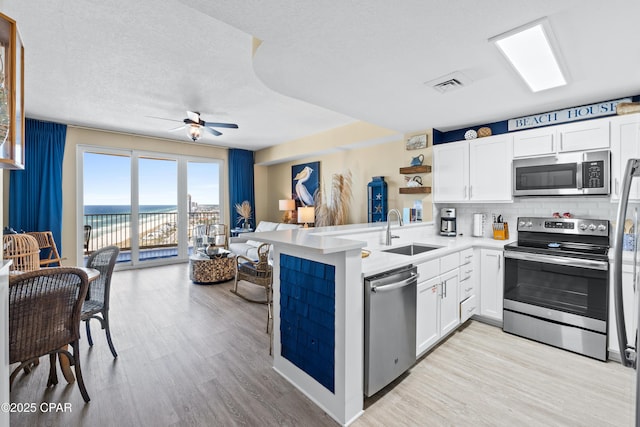 15928 Front Beach Rd Unit 3-2005, Panama City Beach, FL 32413 - kitchen with appliances with stainless steel finishes, open floor plan, ceiling fan, white cabinets, and a textured ceiling