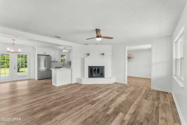 2020 Greenbriar Blvd, Lynn Haven, FL 32444 - unfurnished living room with ceiling fan, wood finished floors, a brick fireplace, a textured ceiling, and a chandelier