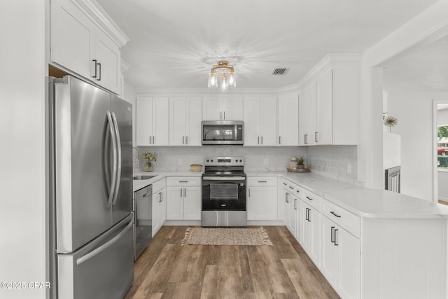 2020 Greenbriar Blvd, Lynn Haven, FL 32444 - kitchen featuring stainless steel appliances, a peninsula, wood finished floors, and white cabinetry