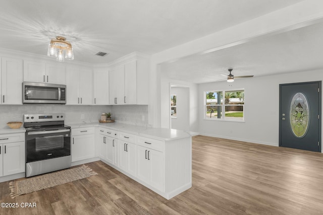 2020 Greenbriar Blvd, Lynn Haven, FL 32444 - kitchen featuring appliances with stainless steel finishes, backsplash, light wood-type flooring, and white cabinetry