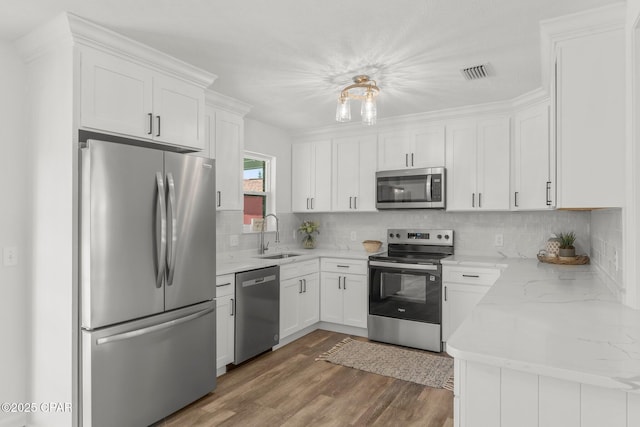 2020 Greenbriar Blvd, Lynn Haven, FL 32444 - kitchen featuring appliances with stainless steel finishes, wood finished floors, white cabinetry, tasteful backsplash, and light stone countertops