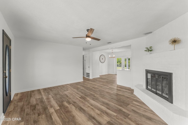 2020 Greenbriar Blvd, Lynn Haven, FL 32444 - unfurnished living room with a brick fireplace, a ceiling fan, wood finished floors, a chandelier, and a textured ceiling